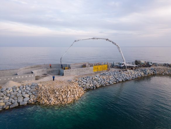 Construction of a reinforced concrete breakwater on a rubblemound foundation, designed to protect the coastline from wave action and erosion. Heavy-duty equipment and precision engineering ensure the stability and longevity of this critical coastal infrastructure.